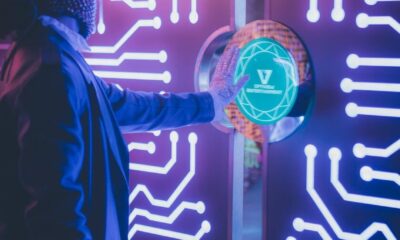 A person interacts with a neon-illuminated futuristic tech panel in a dark room.