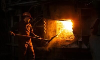 Blue-collar worker managing furnace in an industrial plant setting.