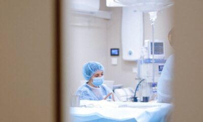 View of a surgeon working in an operating room through a door window, emphasizing medical precision.