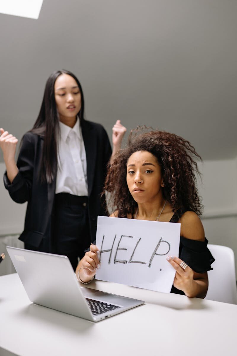 A woman holding a help sign, depicting workplace harassment in an office setting.