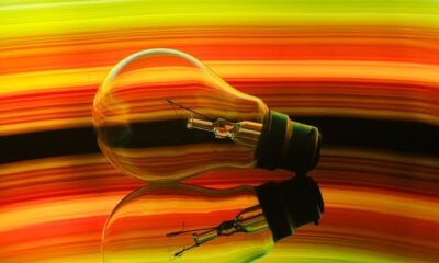 Colorful abstract of a light bulb reflecting on a surface with a vibrant rainbow gradient.