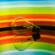 Colorful abstract of a light bulb reflecting on a surface with a vibrant rainbow gradient.