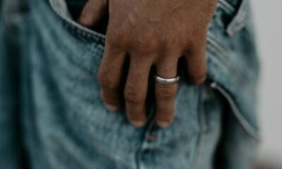Close-up of a man wearing a pearl bracelet and ring with his hand in a denim pocket.