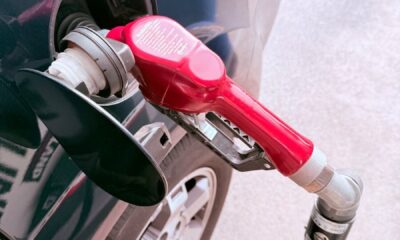 Close-up of a red gas pump fueling a car at a gas station, depicting the refueling process.