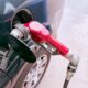 Close-up of a red gas pump fueling a car at a gas station, depicting the refueling process.