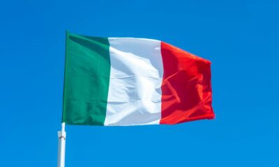 The Italian flag waves vibrantly against a clear blue sky, symbolizing national pride.