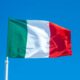 The Italian flag waves vibrantly against a clear blue sky, symbolizing national pride.