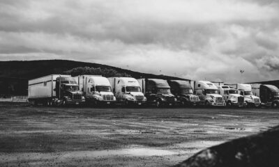 Row of parked semi trucks in a rainy lot, captured in a dramatic black and white setting.