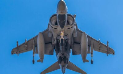 A military jet captured mid-air against a clear blue sky near Albacete, Spain.