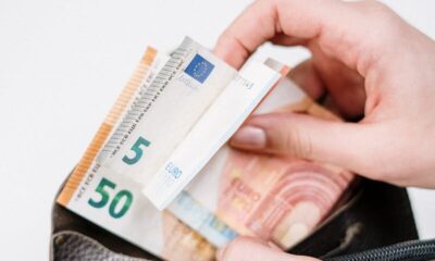 Close-up of hands with euro banknotes being placed in a wallet. Ideal for finance-related content.