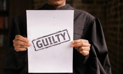 A judge in a courtroom holding a paper with a guilty verdict, symbolizing law and justice.