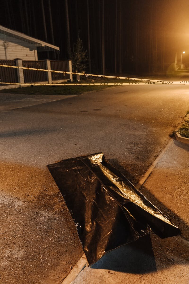 Crime scene at night with evidence bag and caution tape. Urban street setting.