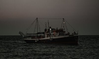 A fishing boat sails on the open sea at twilight, with dim lighting capturing a serene maritime scene.