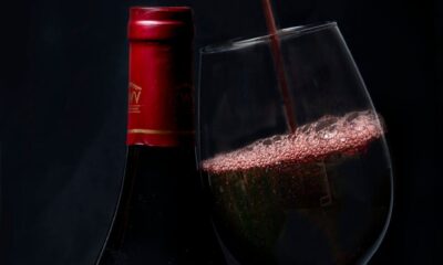 Elegant red wine pouring into a glass with a bottle in background, perfect for wine enthusiasts.