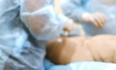 Doctors in surgical gear performing surgery in a hospital setting.