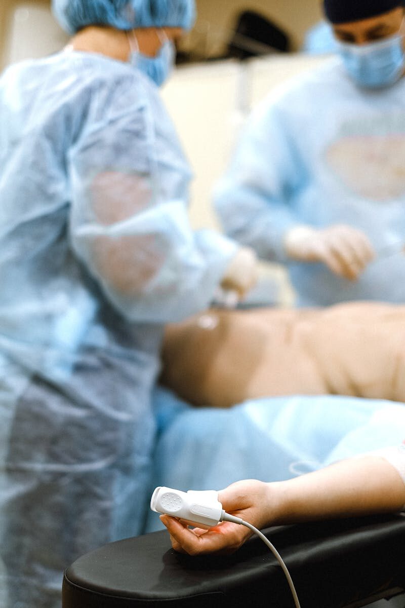 Doctors in surgical gear performing surgery in a hospital setting.
