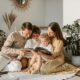 A joyful family shares a book indoors, surrounded by houseplants, promoting reading and togetherness.