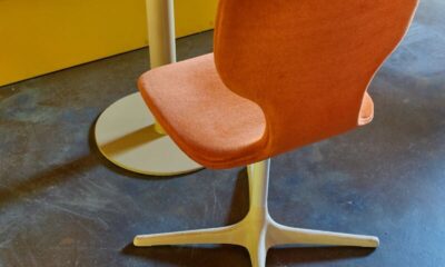 Contemporary orange chair with round table against yellow bench, showcasing modern interior décor.