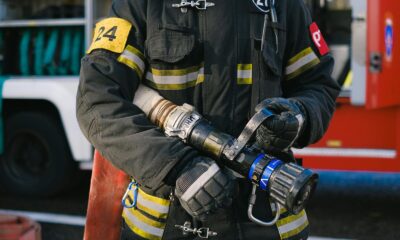 Firefighter in protective gear holding a hose nozzle, ready for action.