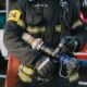 Firefighter in protective gear holding a hose nozzle, ready for action.