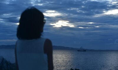 a woman looking at a boat in the ocean