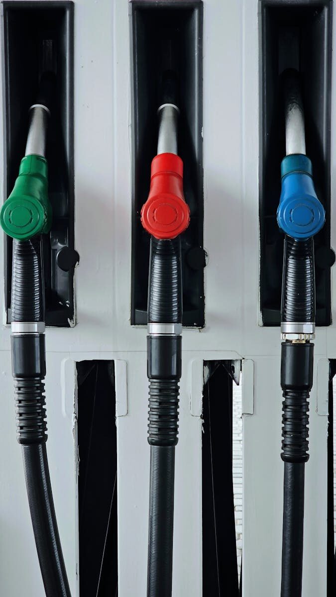Close-up of vibrant green, red, and blue gas pump handles at a station.