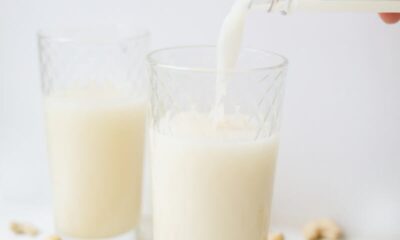 Delicious cashew milk being poured into a glass surrounded by cashews, showcasing refreshing plant-based nutrition.