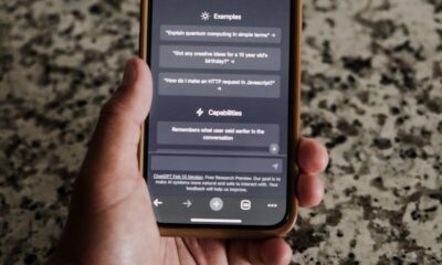 A close-up of a hand holding a smartphone with ChatGPT interface on display.