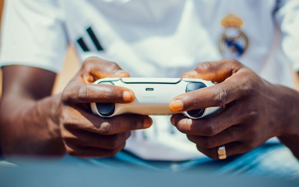 Focused gamer holds a controller, engrossed in a game, wearing team jersey.