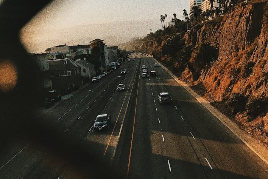 From above of contemporary cars driving on smooth surface of roadway near hills and houses
