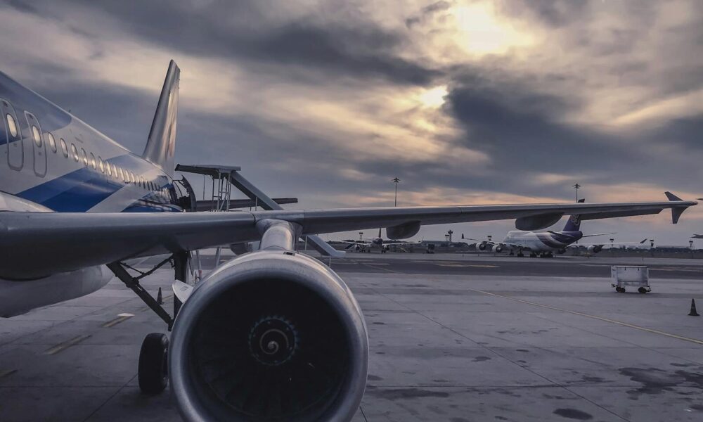A passenger airplane is parked on the tarmac at sunset, with another aircraft in the background.