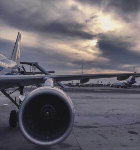 A passenger airplane is parked on the tarmac at sunset, with another aircraft in the background.