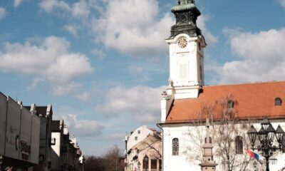 A picturesque view of the historic town square and Town Hall in Sombor, Serbia, under a bright sky.