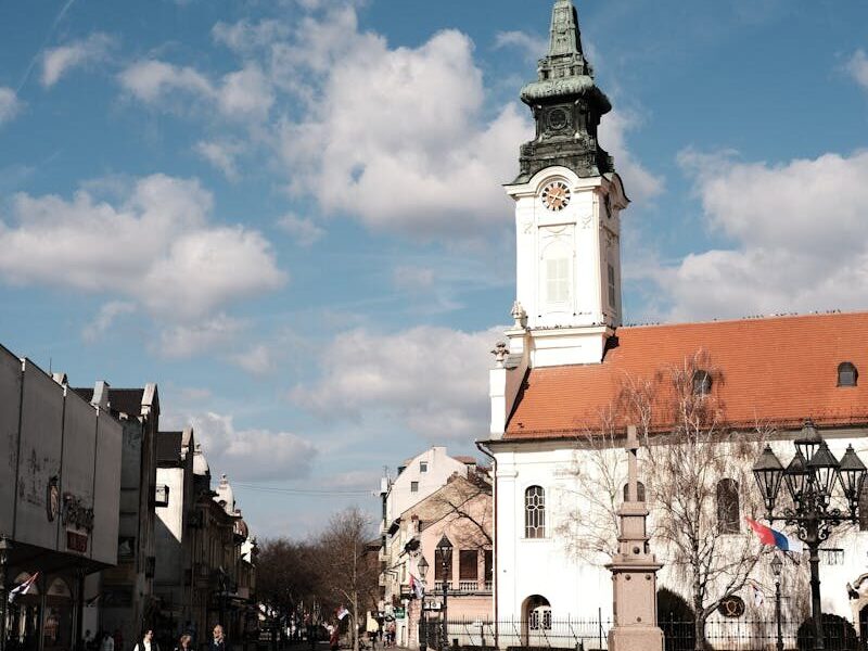 A picturesque view of the historic town square and Town Hall in Sombor, Serbia, under a bright sky.