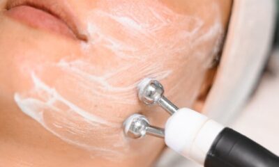Close-up of a woman getting a facial treatment with a massager and face cream in a spa setting.