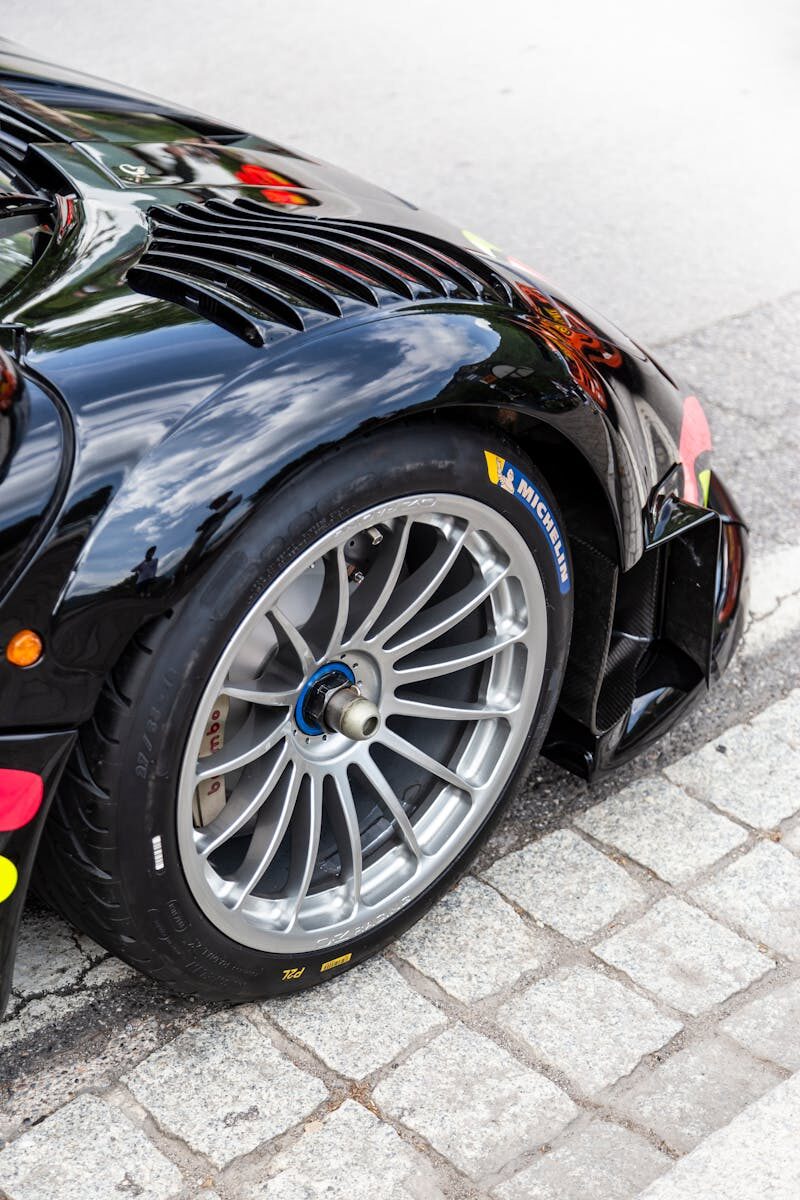 Modern black racing car highlighting sleek design and racing tire close-up for automotive enthusiasts.