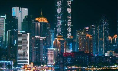 Chongqing skyline illuminated at night with neon lights reflecting on the river, showcasing urban futuristic architecture.
