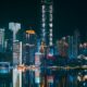 Chongqing skyline illuminated at night with neon lights reflecting on the river, showcasing urban futuristic architecture.