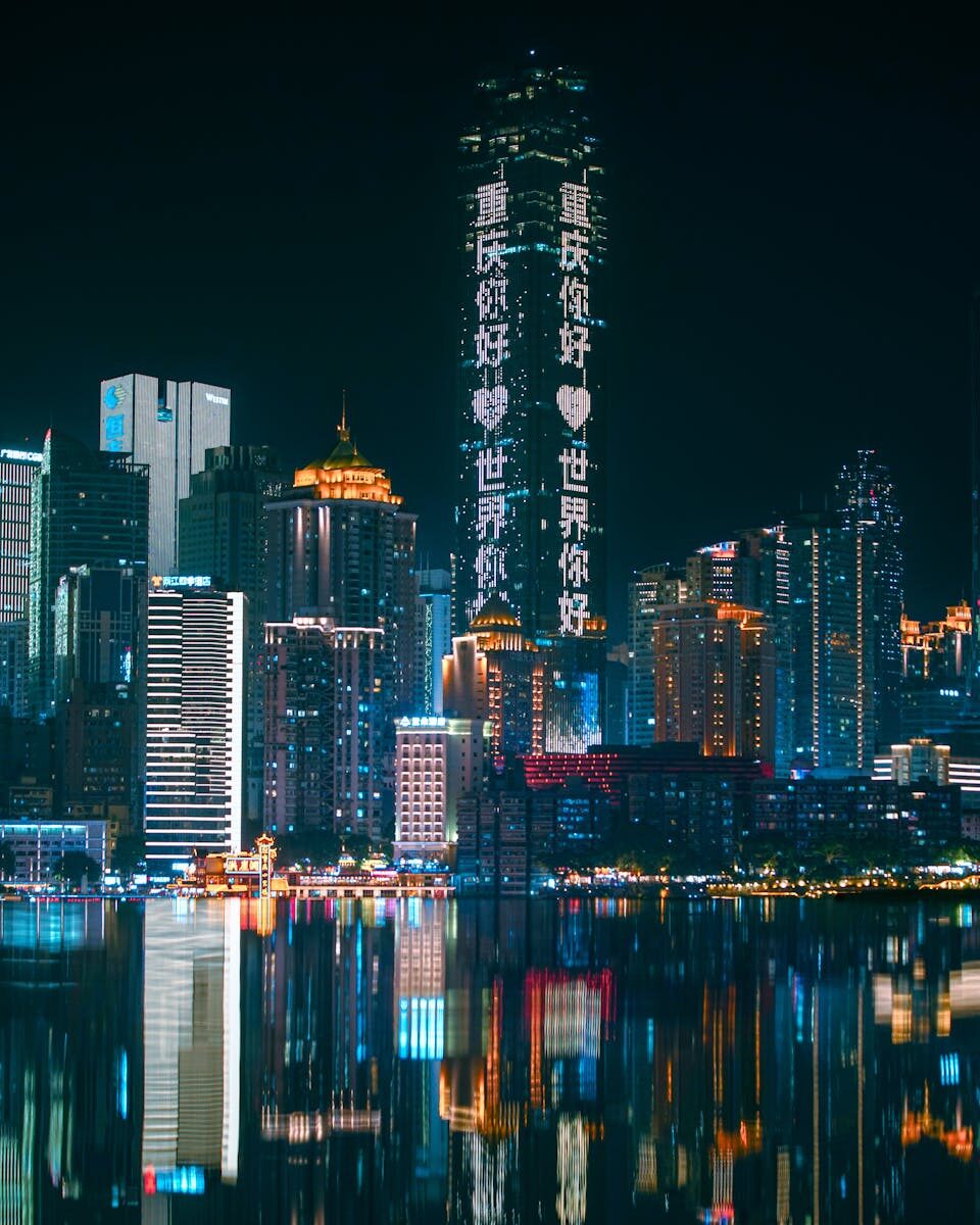 Chongqing skyline illuminated at night with neon lights reflecting on the river, showcasing urban futuristic architecture.