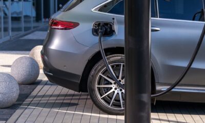 A silver electric car charging at an urban station, highlighting sustainable living in a modern cityscape.