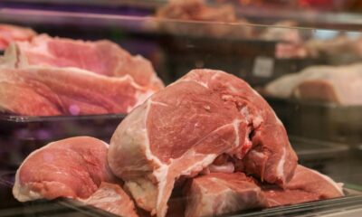 Close-up of fresh raw pork cuts on display in a glass case at a market.