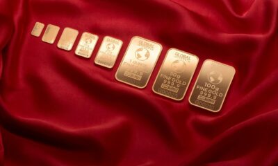Array of fine gold bars displayed on rich red fabric, symbolizing wealth and luxury.
