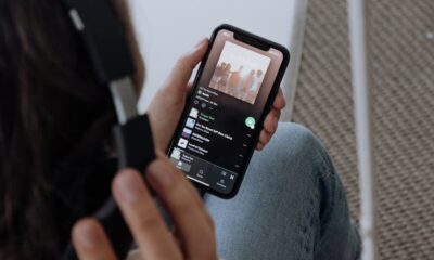 A young woman wearing headphones, relaxing at home, listens to music on her smartphone.
