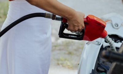 A woman refueling a car at an outdoor gas station, focusing on the fuel pump.