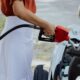 A woman refueling a car at an outdoor gas station, focusing on the fuel pump.