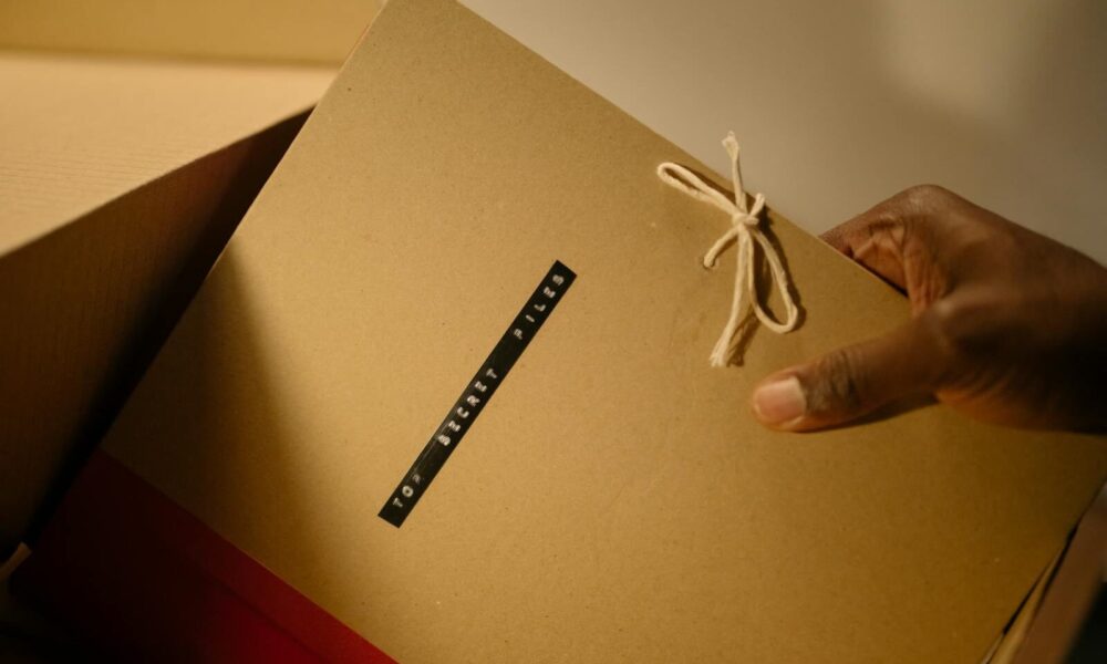 Close-up of hand holding top secret document folder in a box.