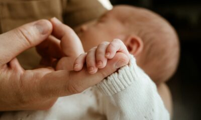 Adult hand holding a newborn baby's hand