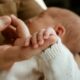Adult hand holding a newborn baby's hand