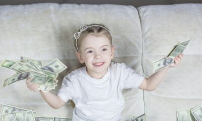 a little girl sitting on a couch holding money