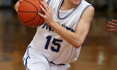 Teen male basketball player in action on indoor court during a game.